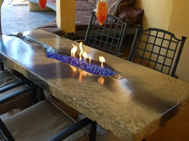 In the picture I can see a table which has fire in between it and there are two chairs on either...
